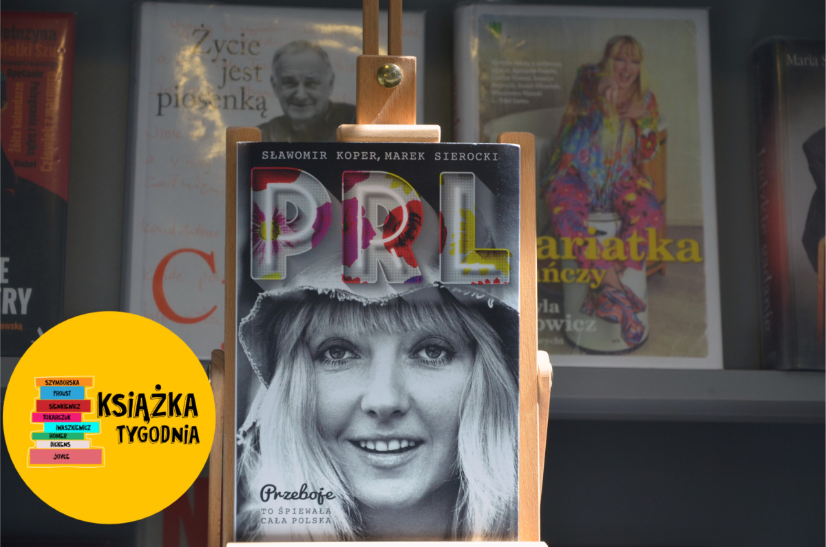 Okładka książki pt. „PRL. Przeboje – to śpiewała cała Polska" autorstwa Sławomira Kopra i Marka Sierockiego, ustawiona na drewnianym sztaludze. Na okładce widnieje czarno-białe zdjęcie uśmiechniętej kobiety w kapeluszu oraz kolorowy, kwiecisty napis „PRL". W lewym dolnym rogu grafika z napisem „Książka Tygodnia" na żółtym tle z kolorowymi grzbietami książek. W tle nieostro widoczne inne książki na półce, m.in. „Życie jest piosenką".